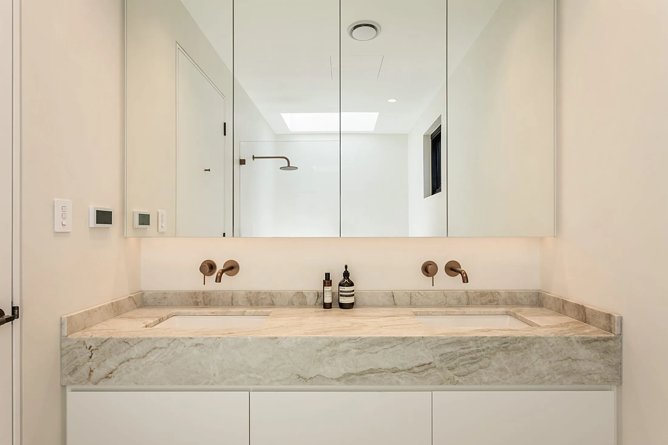 Double vanity with stone top, brass wall taps and mirrored cabinets, Lilyfield